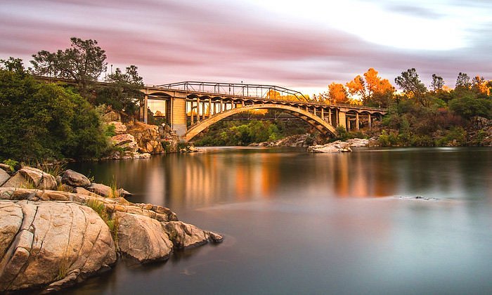 rainbow bridge spanning the american river with granite bluffs and autumn trees in folsom